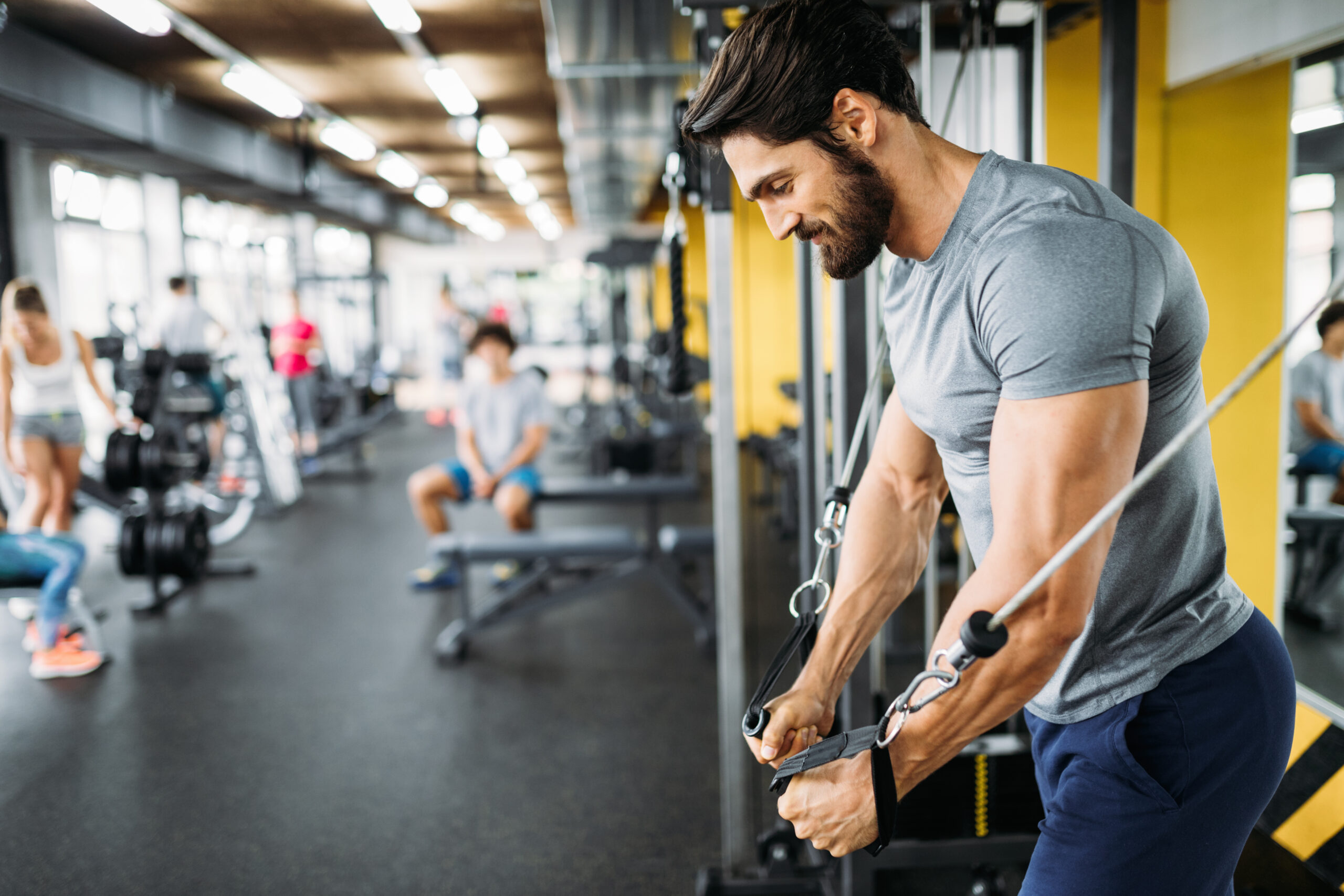 Muscular bodybuilder guy doing exercises with dumbbells in gym